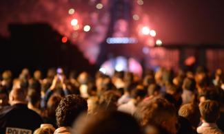 People celebrating in front of the Eiffel Tower at night.
